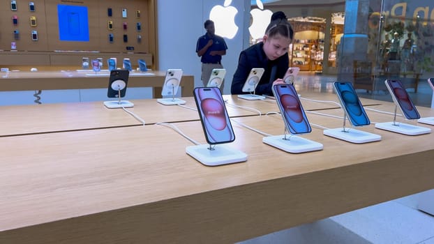 Denver, Colorado, USA-March 23, 2024-curious little girl examines the latest iPhone models on display at the Apple Store located in Park Meadows Mall, showcasing a youthful interest in technology.