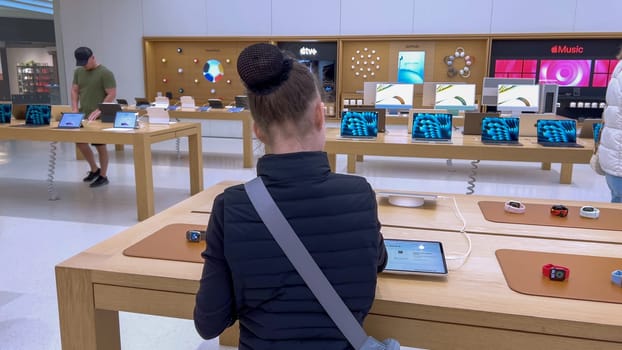 Denver, Colorado, USA-March 23, 2024-curious little girl examines the latest iPhone models on display at the Apple Store located in Park Meadows Mall, showcasing a youthful interest in technology.