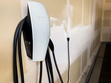Denver, Colorado, USA-March 28, 2024-Tesla Wall Connector, ready to charge an electric vehicle, is mounted on the wall of a residential garage, showcasing the convenience of home EV charging.