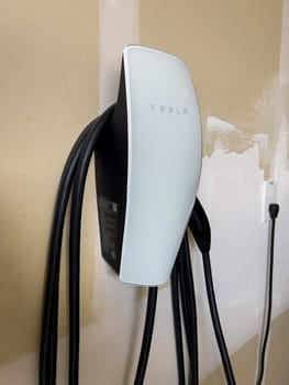 Denver, Colorado, USA-March 28, 2024-Tesla Wall Connector, ready to charge an electric vehicle, is mounted on the wall of a residential garage, showcasing the convenience of home EV charging.