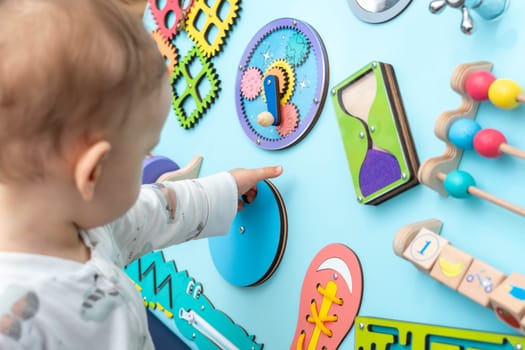 Baby with a small hand reaches for a busy board.