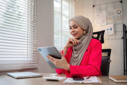 Confident Muslim businesswoman supervisor checks work on holiday and works in home office.