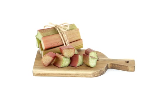 Variety of rhubarb stalks of varying colors from pale green to deep red on wooden cutting board isolated on white background
