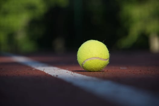 Yellow tennis ball on hard court surface near white line in low angle view