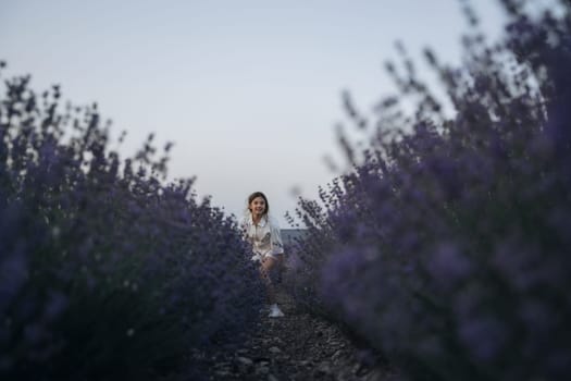 Lavender field happy girl in white dress with a scythe runs through a lilac field of lavender. Aromatherapy travel.