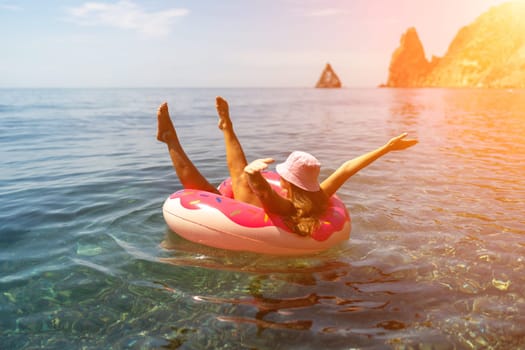 Summer vacation woman in hat floats on an inflatable donut mattress. Happy woman relaxing and enjoying family summer travel holidays travel on the sea