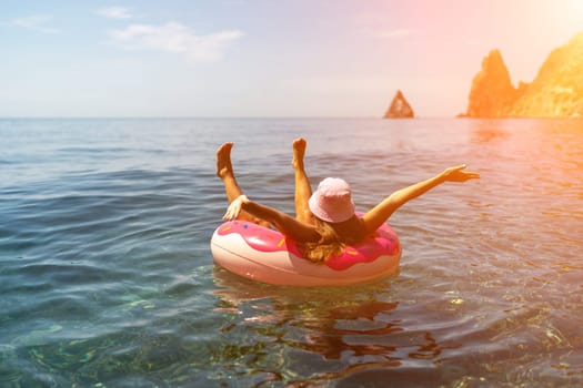 Summer vacation woman in hat floats on an inflatable donut mattress. Happy woman relaxing and enjoying family summer travel holidays travel on the sea