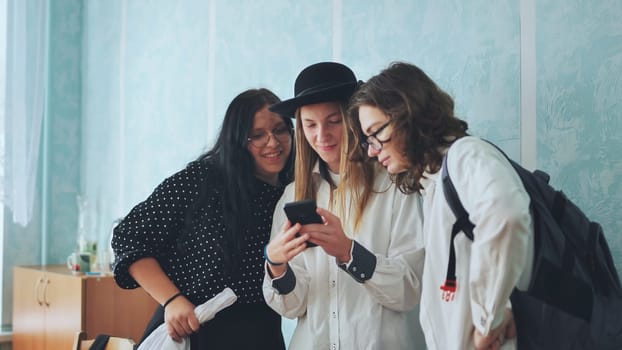 Three girls schoolgirl. Summer in the street. In his hands holds a smartphone. In jeans clothes, sunglasses. The concept of children in social networks. Write a message on the Internet.