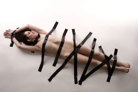 BDSM. Nude woman posing with duct tape on her body