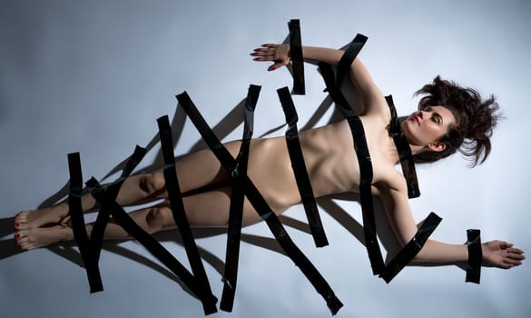 Concept. Naked body of woman covered with black duct tape