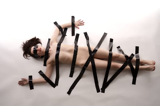 BDSM concept. Blindfolded nude woman tied with duct tape