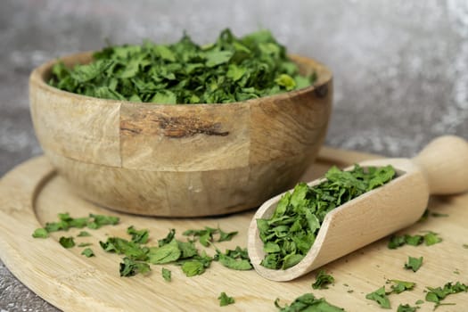 Dry parsley spice with wooden spoon in wooden bowl. Homegrown herbs and spices for cooking. Fresh dried aromatic natural food ingredients. Copy space