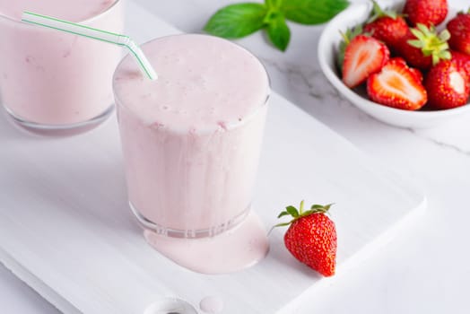 Yogurt , buttermilk or kefir with strawberry. Yogurt in glass on light background. Probiotic cold fermented dairy drink. Gut health, fermented products, healthy gut flora concept.