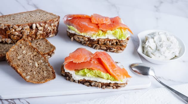 Healthy toasts with rye bread with cream cheese, salmon and salad.
