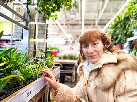 Middle-Aged girl in a flower and plant shop. Mature Woman Shopping for Seedlings at Plant Nursery in Spring