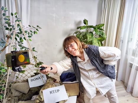 Middle-Aged Blogger Woman shoots on a smartphone Sorting Belongings With KonMari Method. Mature woman categorizes items