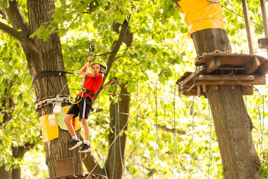 Adorable little girl enjoying her time in climbing adventure park on warm and sunny summer day.