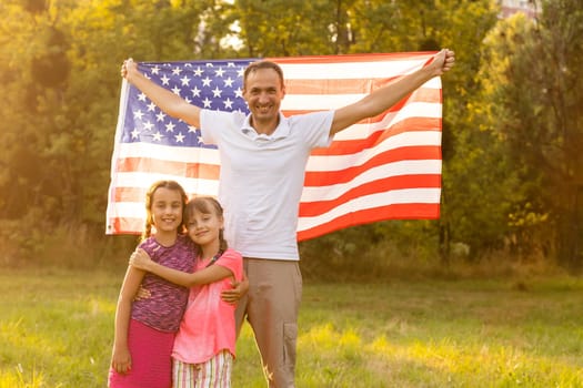 happy family with the flag of america USA at sunset outdoors.