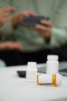 Medicine bottles on table with senior couple sitting on background. healthcare, pharmaceutical concept.