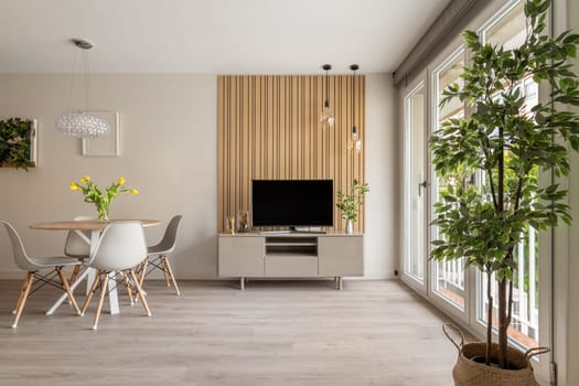 Spacious living room featuring a wooden panel wall with suspended lights and a blend of natural and modern decor.