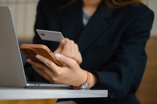 Businesswoman holding credit bank card and using mobile phone for shopping online.