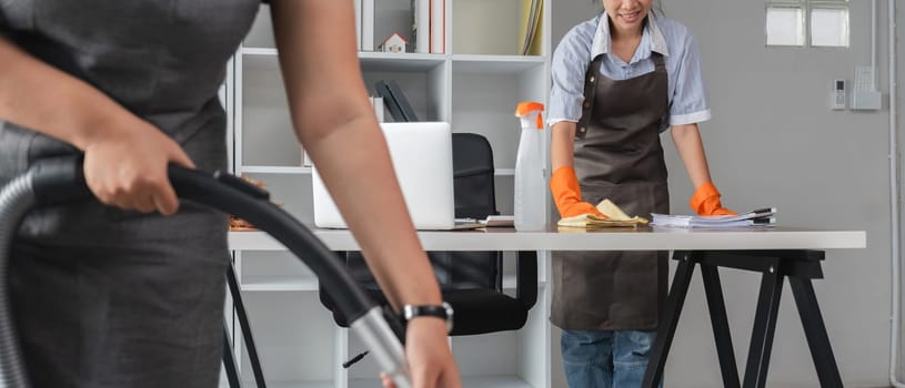 Young Asian housewife uses a vacuum cleaner to clean and vacuum the office..