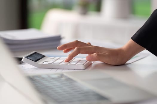 Businesswoman working with document and using calculator for checking finance report.