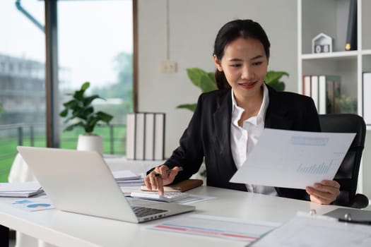 Businesswoman working with document and using calculator for checking finance report.