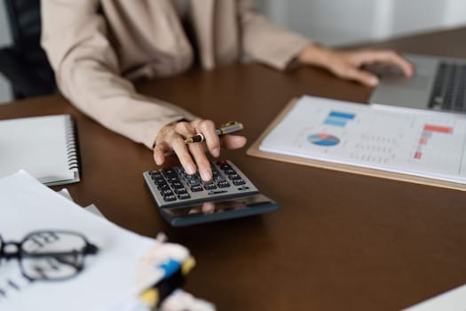 Businesswoman using a calculator to calculate numbers on a company's financial documents, she is analyzing historical financial data to plan how to grow the company. Financial concept.