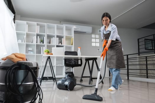 Young Asian housewife uses a vacuum cleaner to clean and vacuum the office..