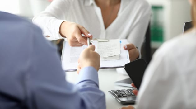 Focus on woman hand holding pen and paper folder with important documents. Businesswoman giving contract for signing to business partner. Biz negotiations concept