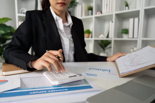 Businesswoman working with document and using calculator for checking finance report.