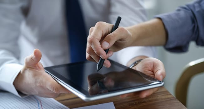 Focus on male hands holding modern tablet. Business partner showing something with stylos. Empty copy space on gadget display. Biz meeting concept. Blurred background