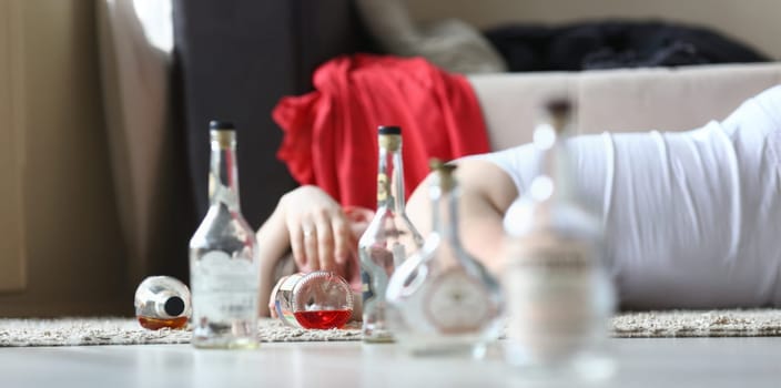 Portrait of male napping after rough night party. Male drunkard sleeping on comfortable sofa and holding bottle of expensive alcohol. Consequences of irresponsible drinking concept