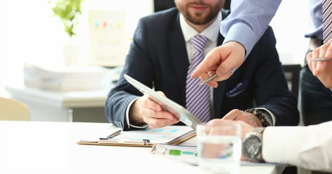 Close-up of smart colleagues working in big modern office and talking about complicated agreement. Young manager explaining boss details hard to understand. Company meeting concept