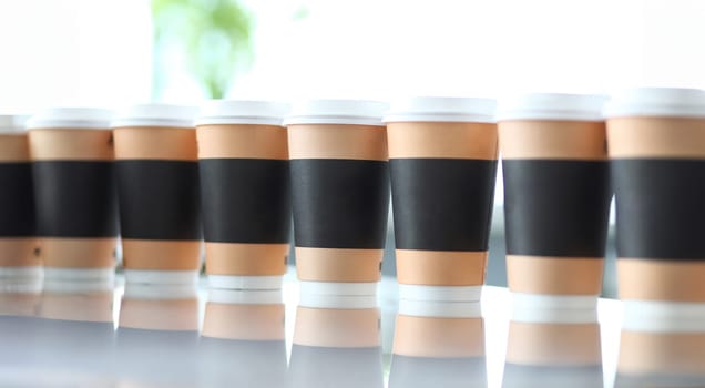 Line of paper cups standing at table closeup