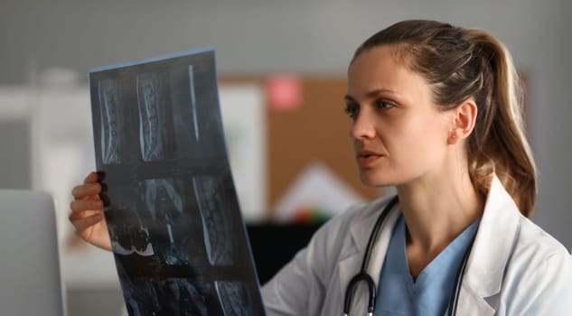 Professional female doctor hold x-ray imge in hand portrait. Medical bone exam concept