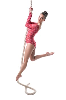 Beautiful gymnast looking at camera while hanging on rope