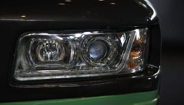 Close-up of blue compact car with new modern design. Headlamp light of black car with electric or hybrid driving system concept. Automotive industry concept