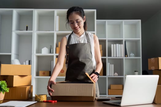 Young business entrepreneur sealing a box with tape. Preparing for shipping, Packing, online selling, e-commerce concept.