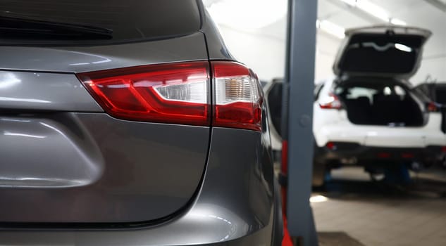 Focus on lamps of modern automobile placed in underground parking. Stylish fashionable business class vehicle metal figure and headlights. Blurred background