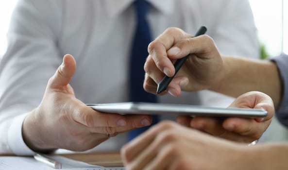 Focus on male hand pointing at screen of modern tablet with stylos. Biz colleagues discussing signing future bargain. Business negotiations concept. Blurred background