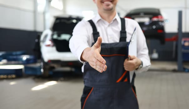 Focus on smart man hand reaching for firm handshake with someone and holding important paper folder with information about different autos. Machinery repairman concept