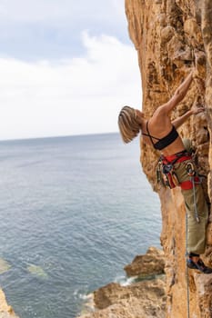A woman is climbing a rock wall while looking out at the ocean. The scene is serene and peaceful, with the woman's focus on the task at hand