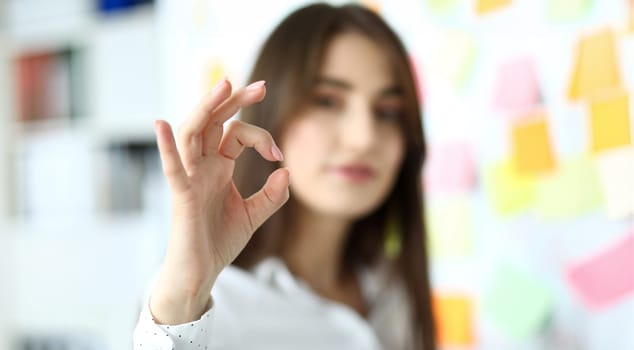 Female clerk showing all right symbol with her fingers at office workplace close-up