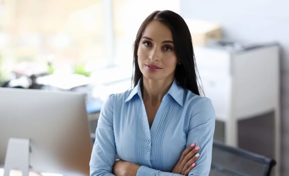 Millennial businesswomen in blue shirt armcrossed office portrait. Business education concept