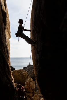 A woman is climbing a rock wall with a rope. The image has a mood of adventure and excitement