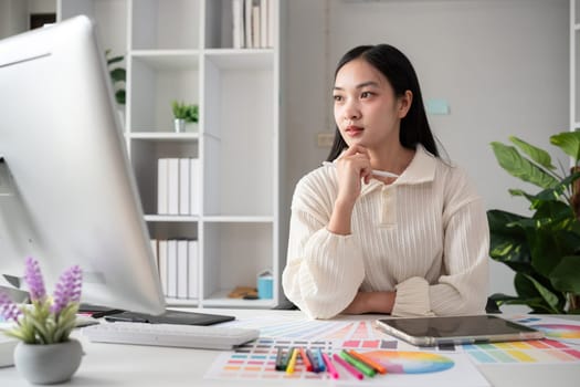 Female designer working in graphic design on computer Sit and choose colors and work intently in your office..