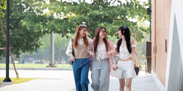 College friends walk to class together. University student in campus talk and have fun outdoors.