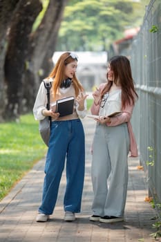 University student girl friends with learning book college while walking in campus.